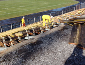 Workers remove the benches in the east side bleachers at Richardson Stadium